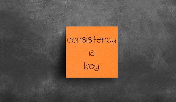 A sticky note that says 'consistency is key'.
