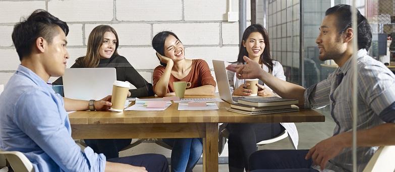 A diverse group of young co-workers discuss ideas at a table.