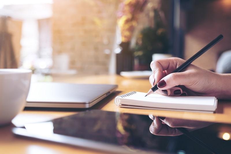 A closeup shot of a woman's hand writing on a notepad.
