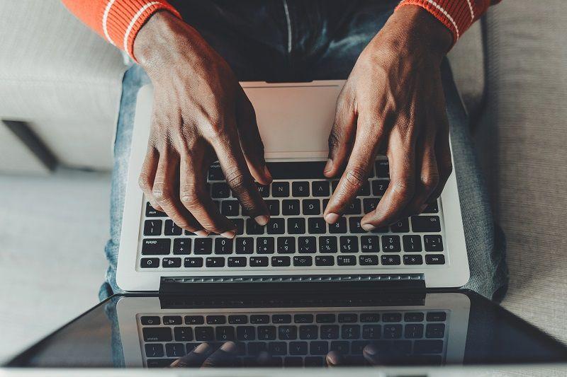 Die Hände eines Mannes, der auf der Tastatur eines Laptops tippt.