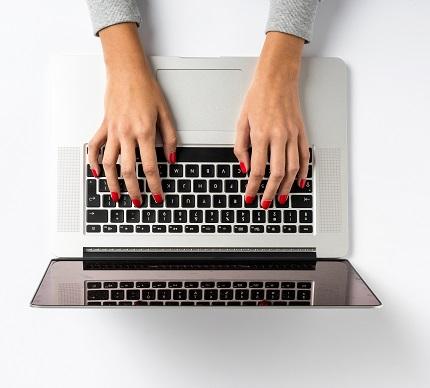 Ein Bild zeigt die Hände einer Frau, die einen Laptop verwendet.