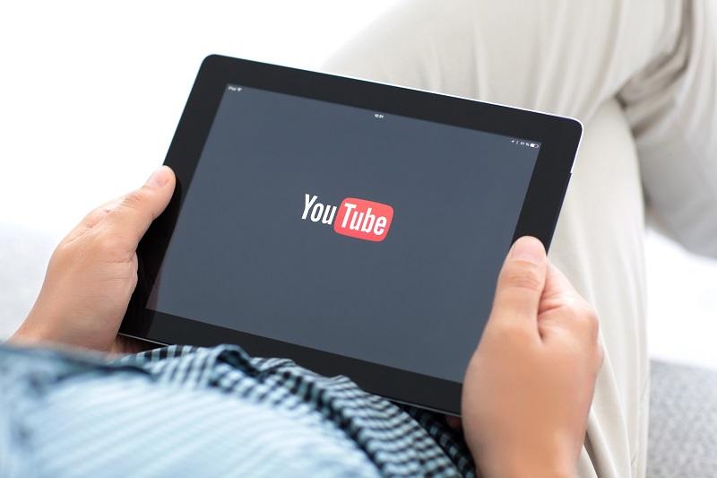 A person holding a tablet using YouTube.