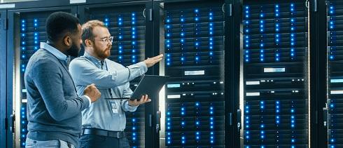 Zwei Techniker mit einem Laptop in einem Serverraum.