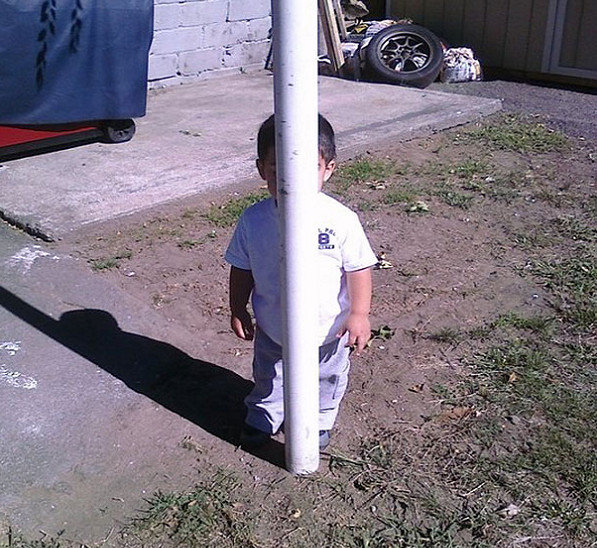 A child hiding behind a pole.
