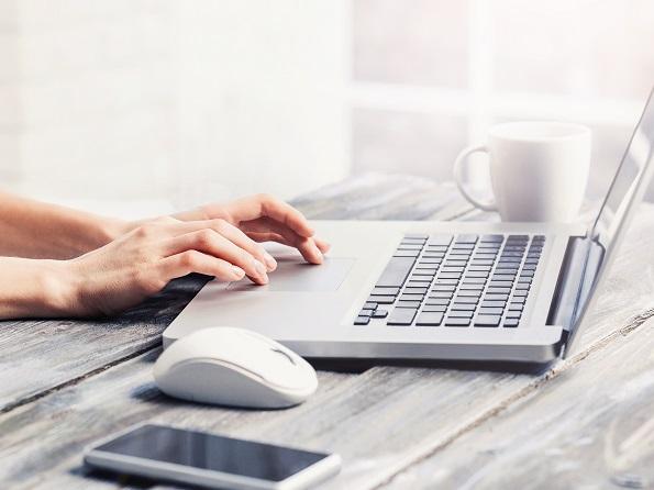 Die Hände einer Frau, die an einem Laptop arbeitet.