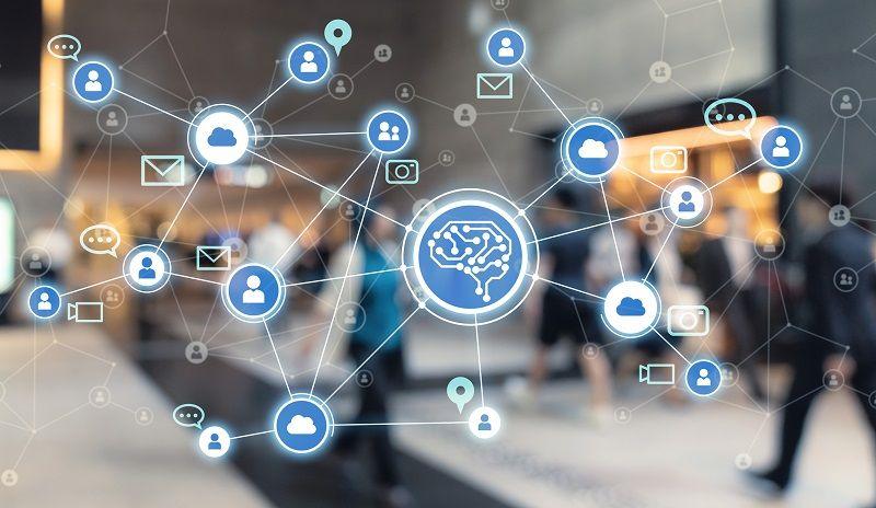 Ein Netzwerk, das aus Symbolen wie Personen und Cloudspeichern besteht, und um einen Knotenpunkt angeordnet ist, auf dem eine Ansammlung aus Schaltkreisen die Form eines Gehirns nachbildet.