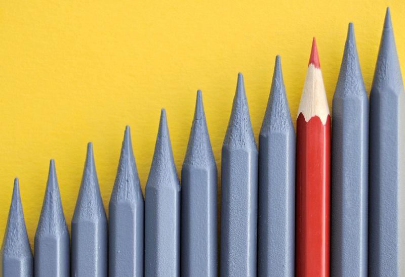 A red pencil among many grey pencils.