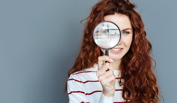 A young woman using a magnifying glass.
