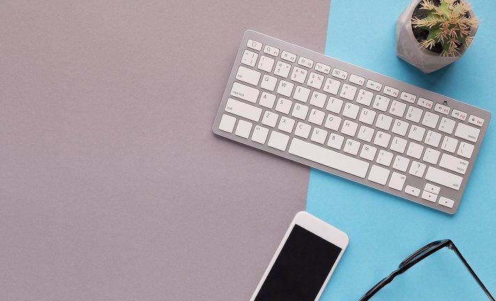 Auf einem Tisch befinden sich ein Kaktus, eine Brille, eine Computertastatur und ein Smartphone.