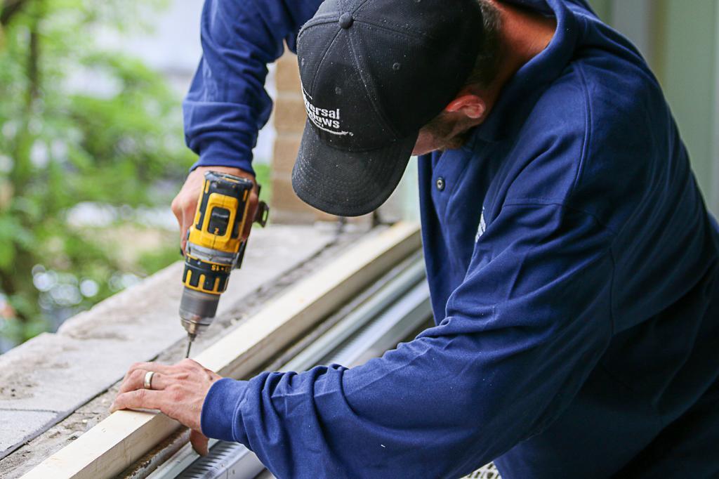 A worker building a window into a frame.