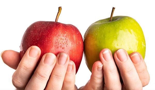 Someone comparing different colored apples.