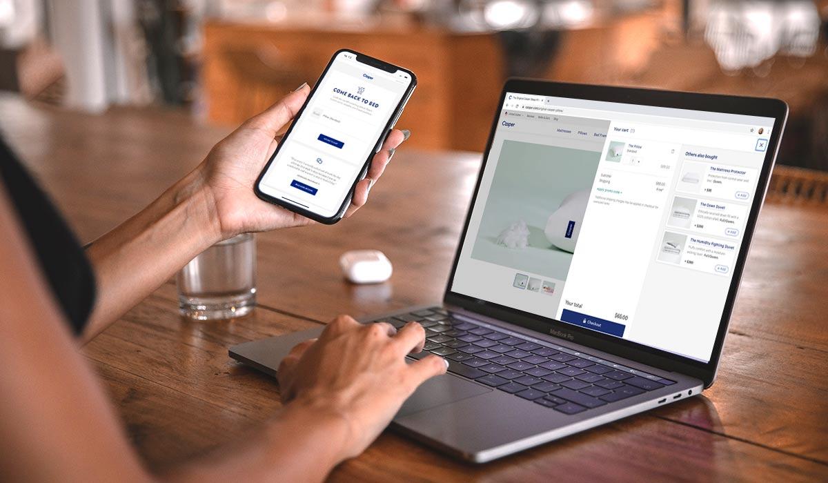Woman holding a phone with an abandoned cart email returning to her cart on Casper's web shop.