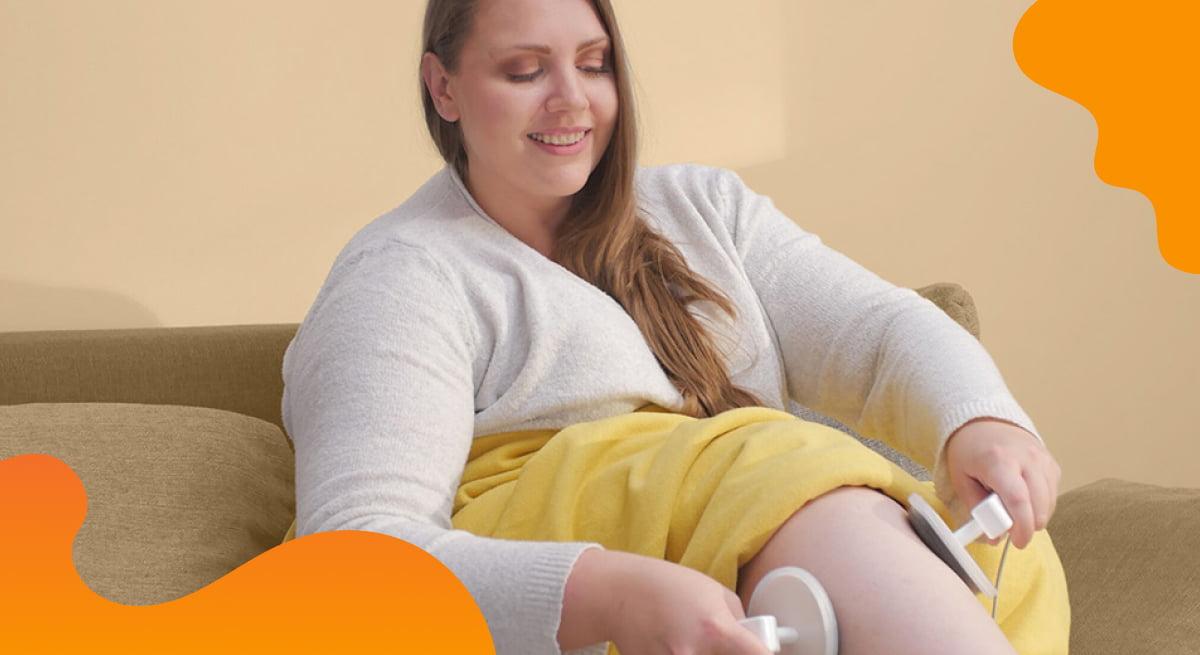 Das Titelbild von Physiomed Elekromedizin in Orange zeigt eine Frau, die ein Medizinprodukt auf ihren Beinen verwendet.