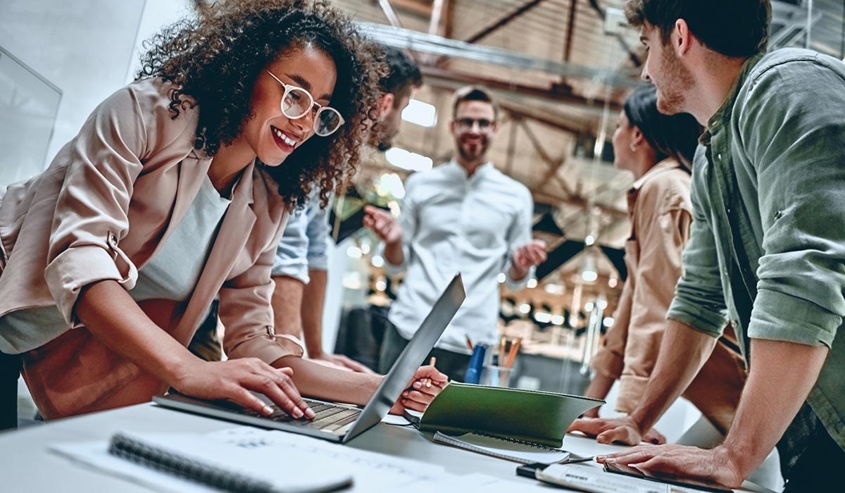 Creative team members gather around a table in an industrial office.