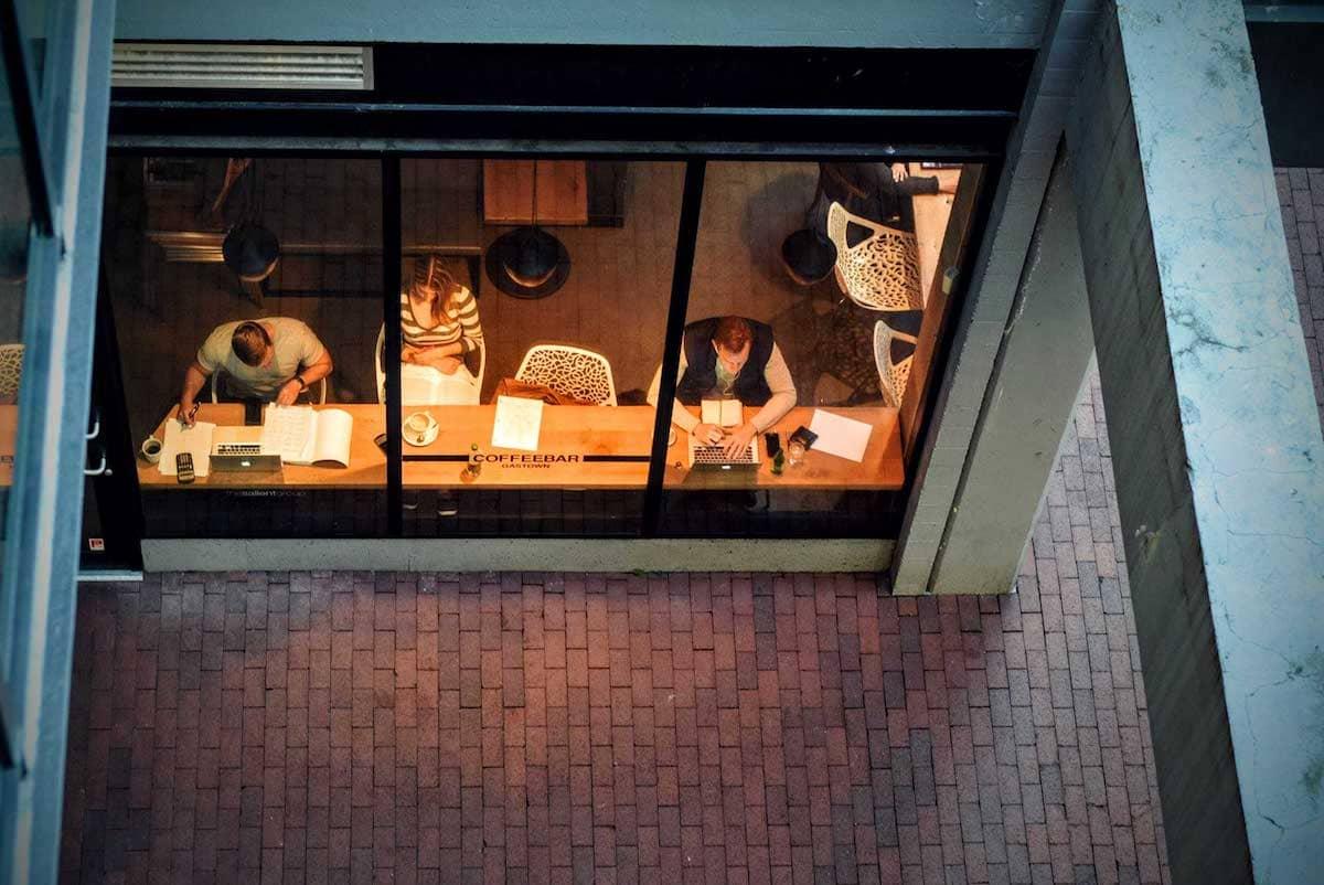 Mehrere Personen arbeiten mit Laptops in einem Café.