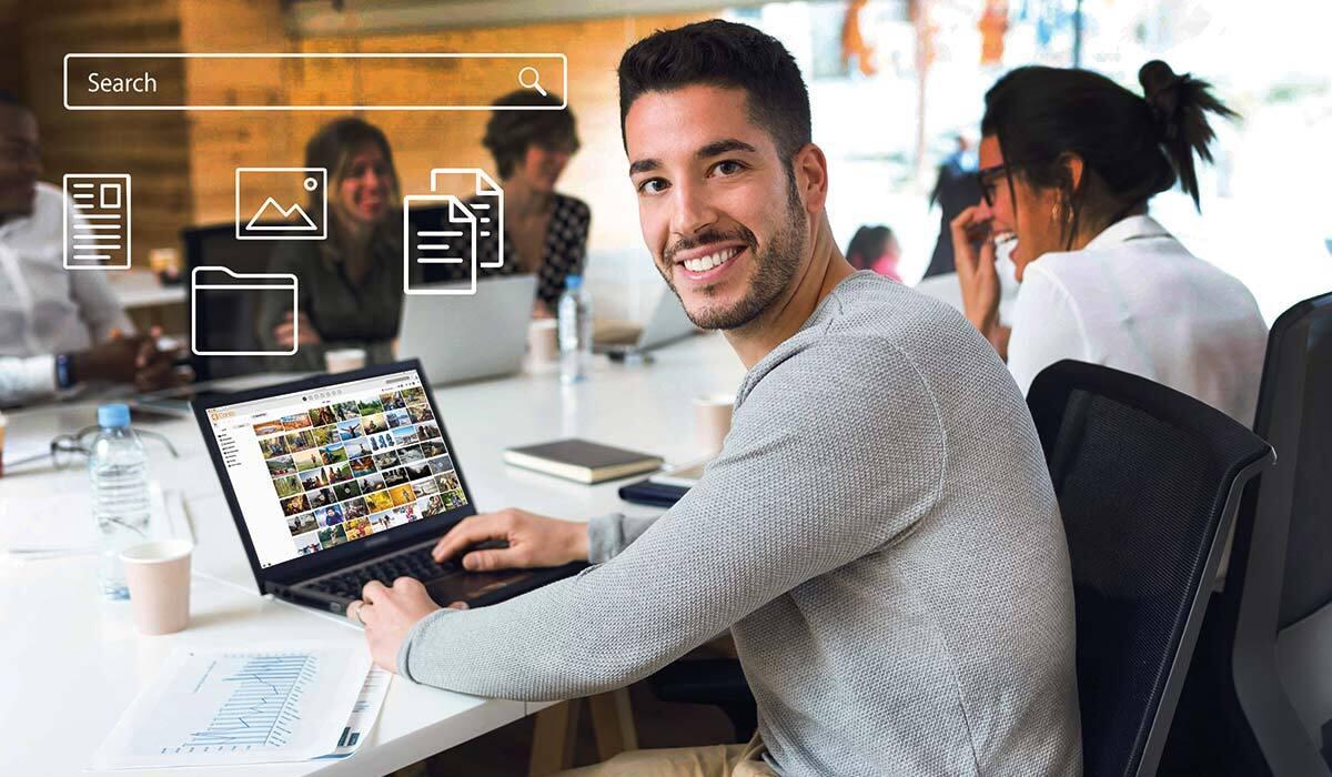Man in a gray shirt using Canto on a laptop in a meeting.