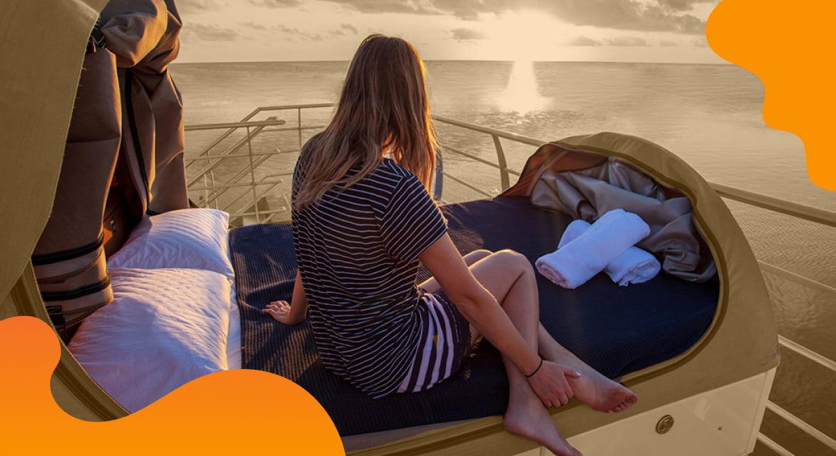 Journey beyond header image in orange showing a woman relaxing in a bed near an ocean.