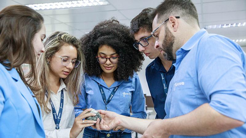 Five Fugro employees examine a geological specimen inside the Fugro office.