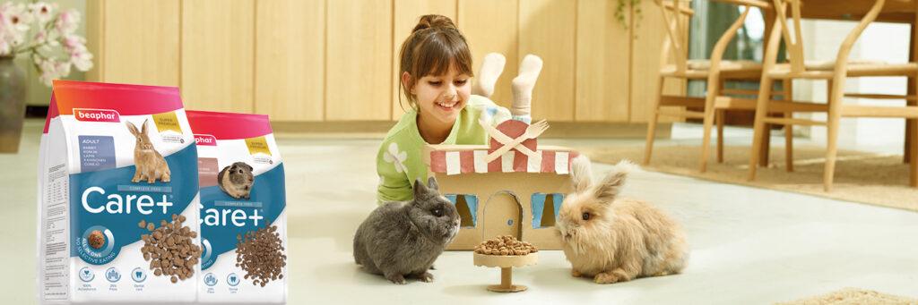 Promoting Beaphar's bunny products with a little girl laying on the ground playing with two bunnies while eating food.