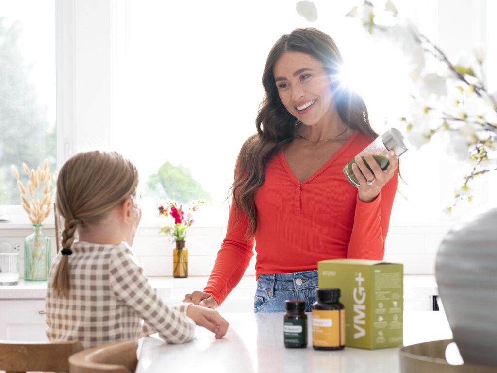 Woman holding green juice while talking to a child.