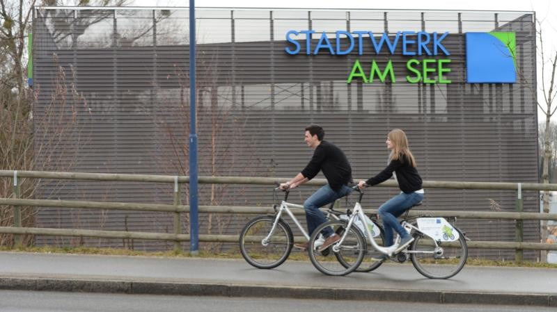 Zwei Radfahrer vor dem Gebäude des Stadtwerk am See.