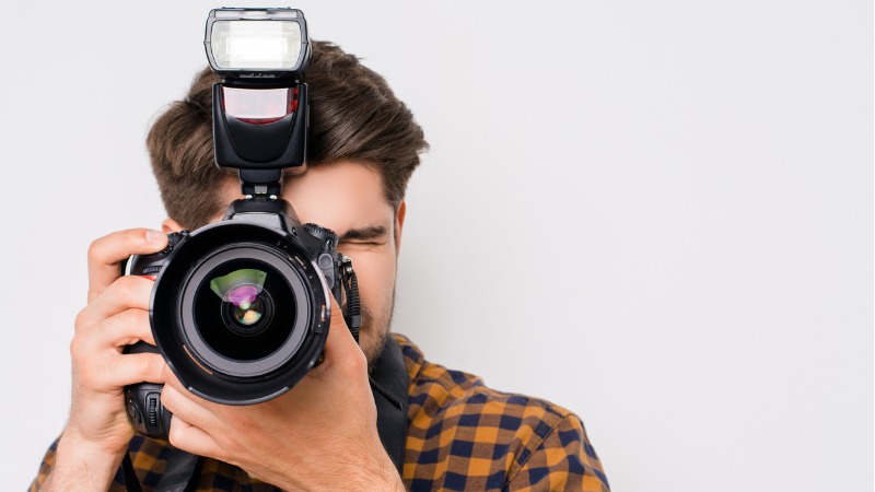 A young, focused looking man is using his camera to take a photo.